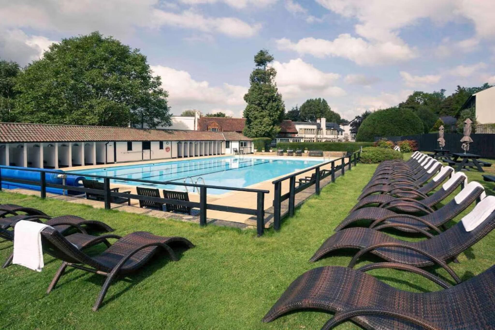 A swimming pool with lounge chairs and a covered seating area.