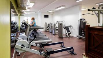 Un gimnasio con cintas de correr, máquinas de pesas y un espejo grande.