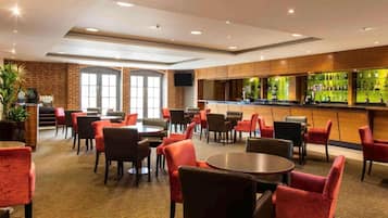 Een hotel lobby met een bar, zitgedeelte en een televisiescherm.