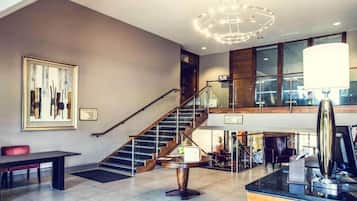 A spacious living area with a staircase, a dining table, and a modern chandelier.