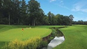 A golf course with a water hazard, trees, and a clear sky. - Sunday Walton Hall Retreat & Spa | Standard Double (Wellesbourne Hastings)