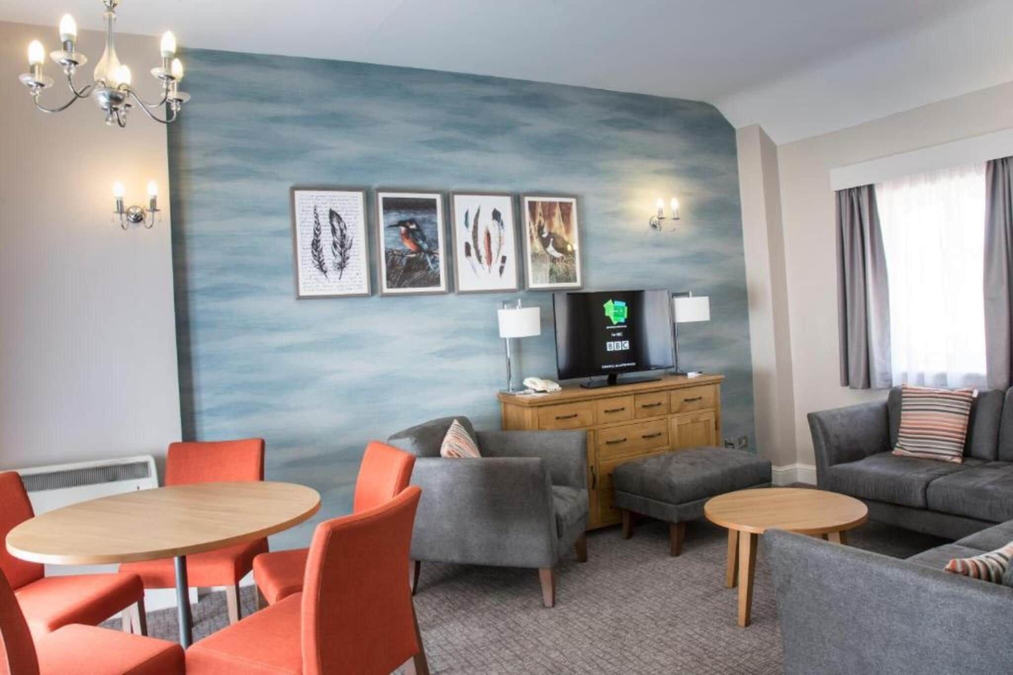 Habitación de hotel con zona de estar, televisor y obra de arte en la pared.