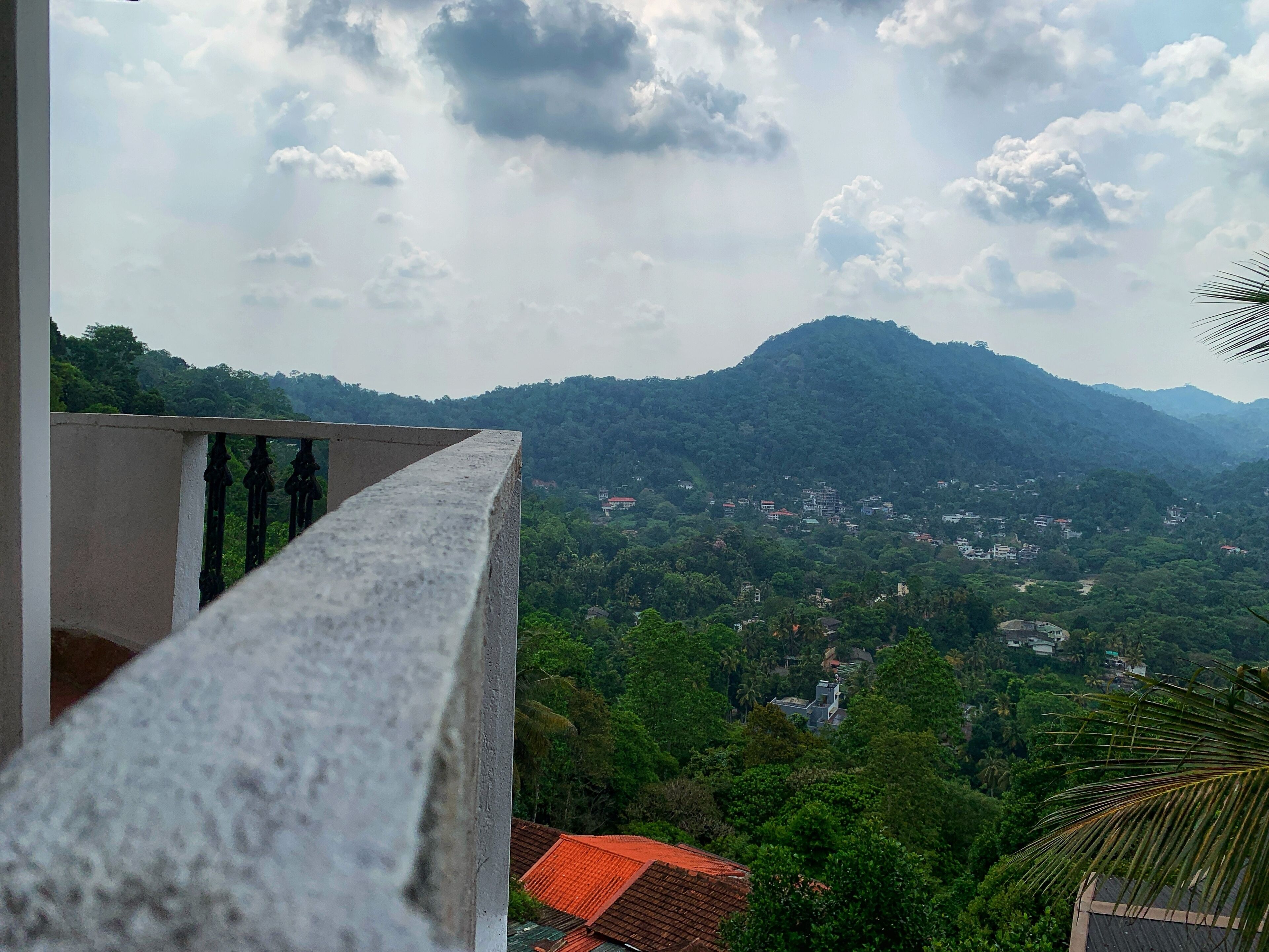 A balcony with a view of a mountainous landscape and scattered buildings.