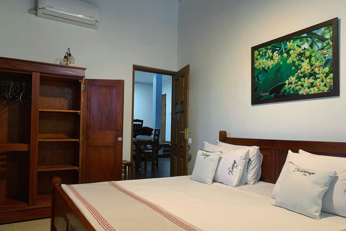 A hotel room with a bed, a wardrobe, a dining area, and a wall-mounted picture.