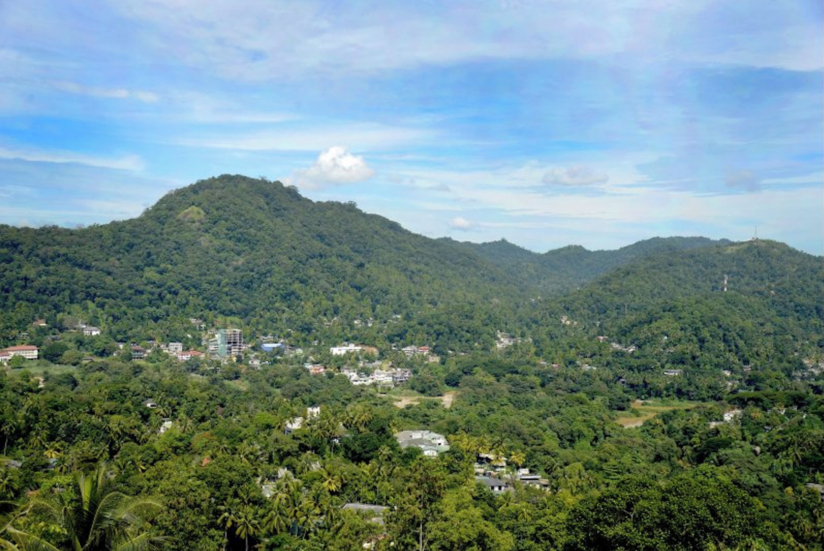 A mountainous landscape with scattered buildings and dense greenery.