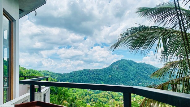 A balcony with a view of a lush green landscape and a mountain in the distance. - The Heritage Inn  (Kandy)