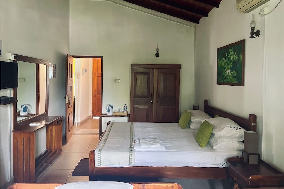 A bedroom with a bed, bedside table, mirror, wardrobe, and a television.