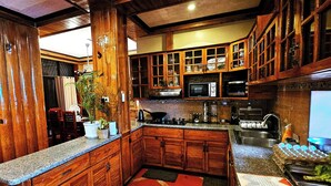 Una cocina con armarios de madera, microondas y pileta.