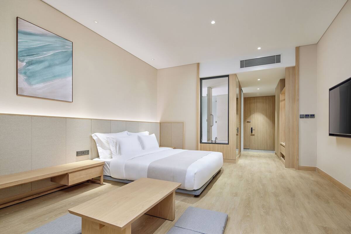 A modern hotel room with a bed, bedside table, and a TV.