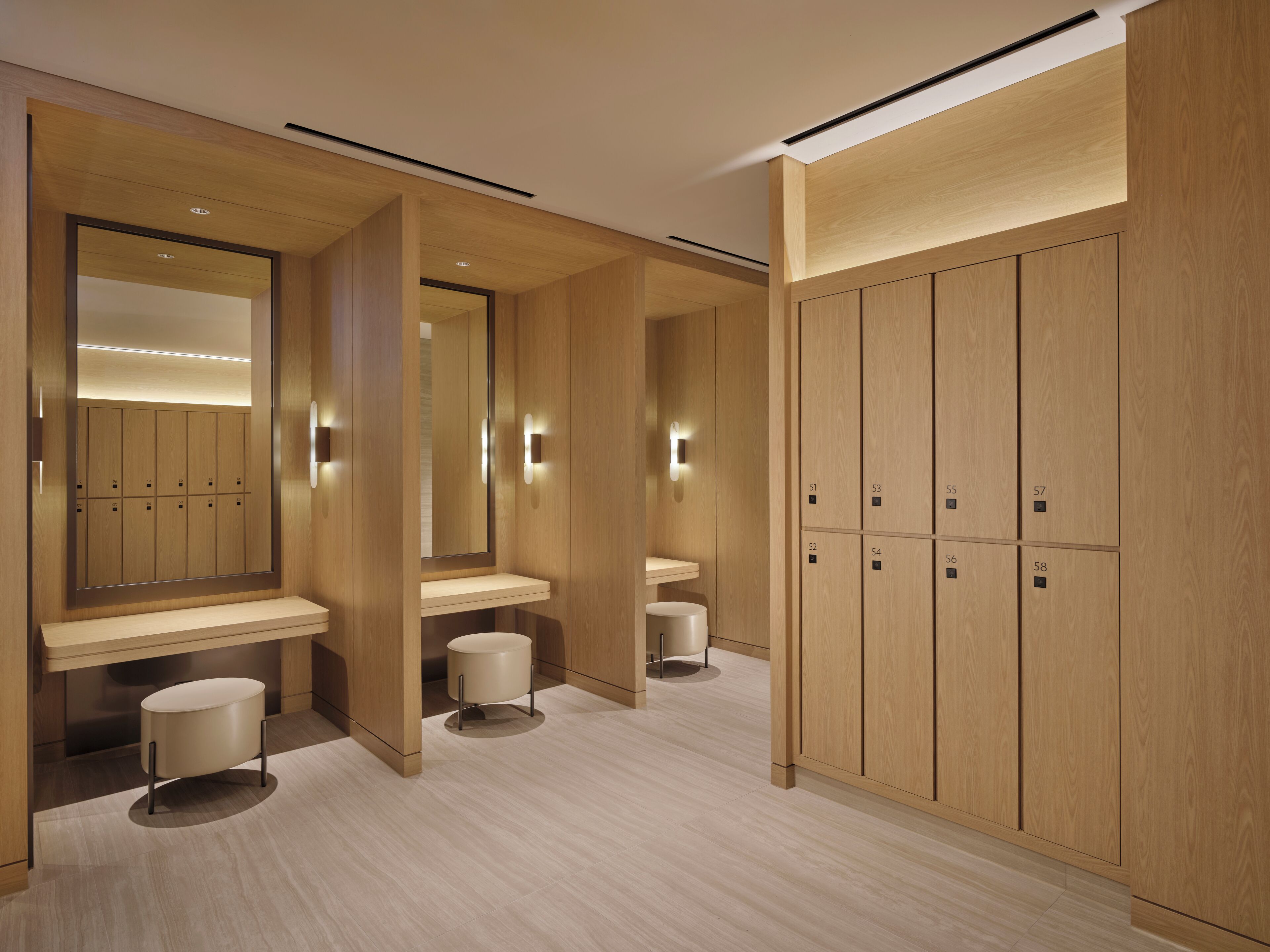 A modern bathroom with wooden lockers, vanity mirrors, and a clean, minimalist design.