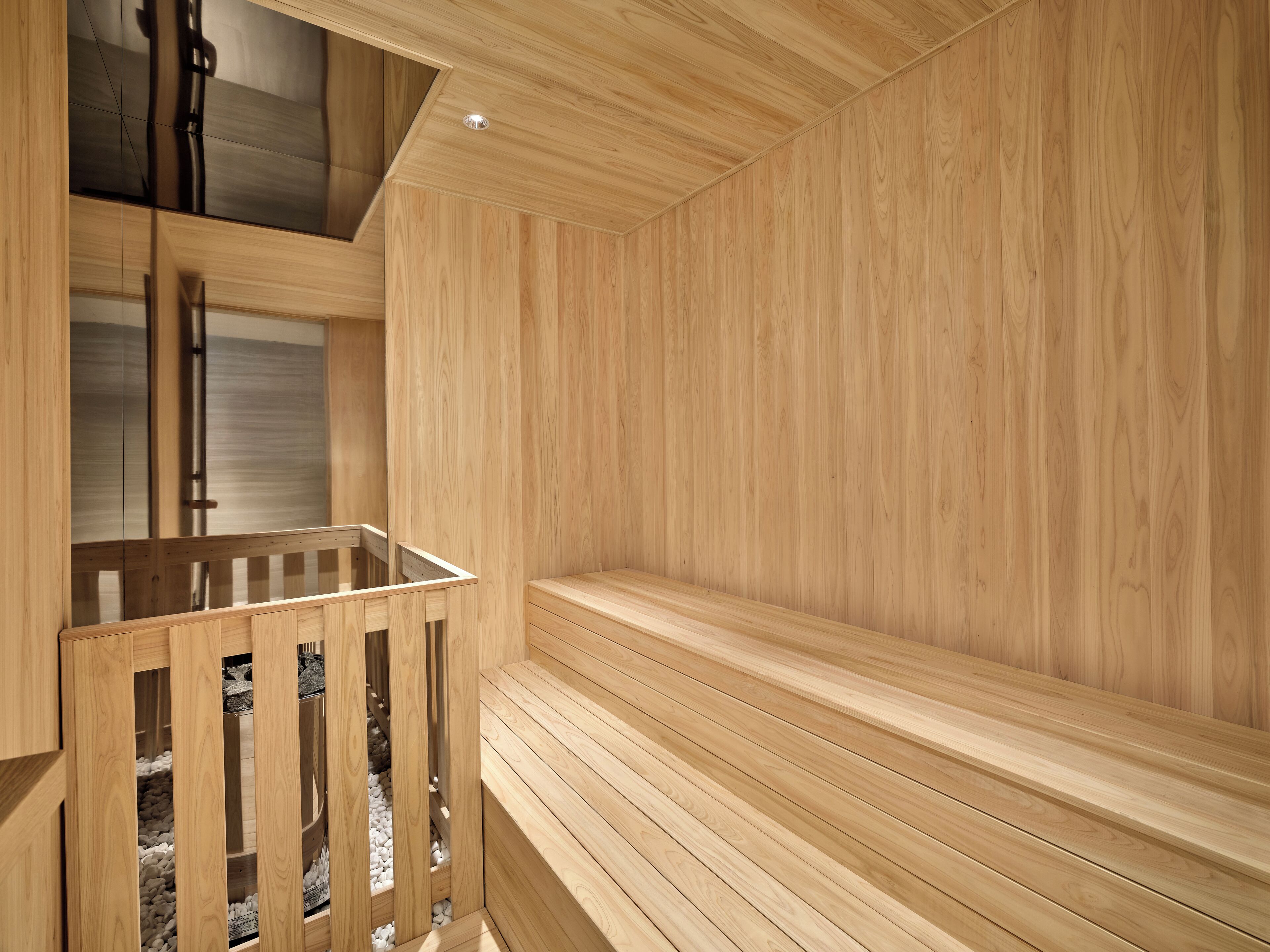 A sauna with wooden benches and a glass-enclosed area with benches.