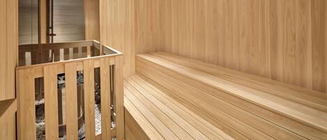 A sauna with wooden benches and a glass-enclosed area with benches.