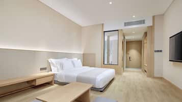 Une chambre d’hôtel moderne équipée d’un lit, d’une table de chevet et d’un téléviseur fixé au mur.