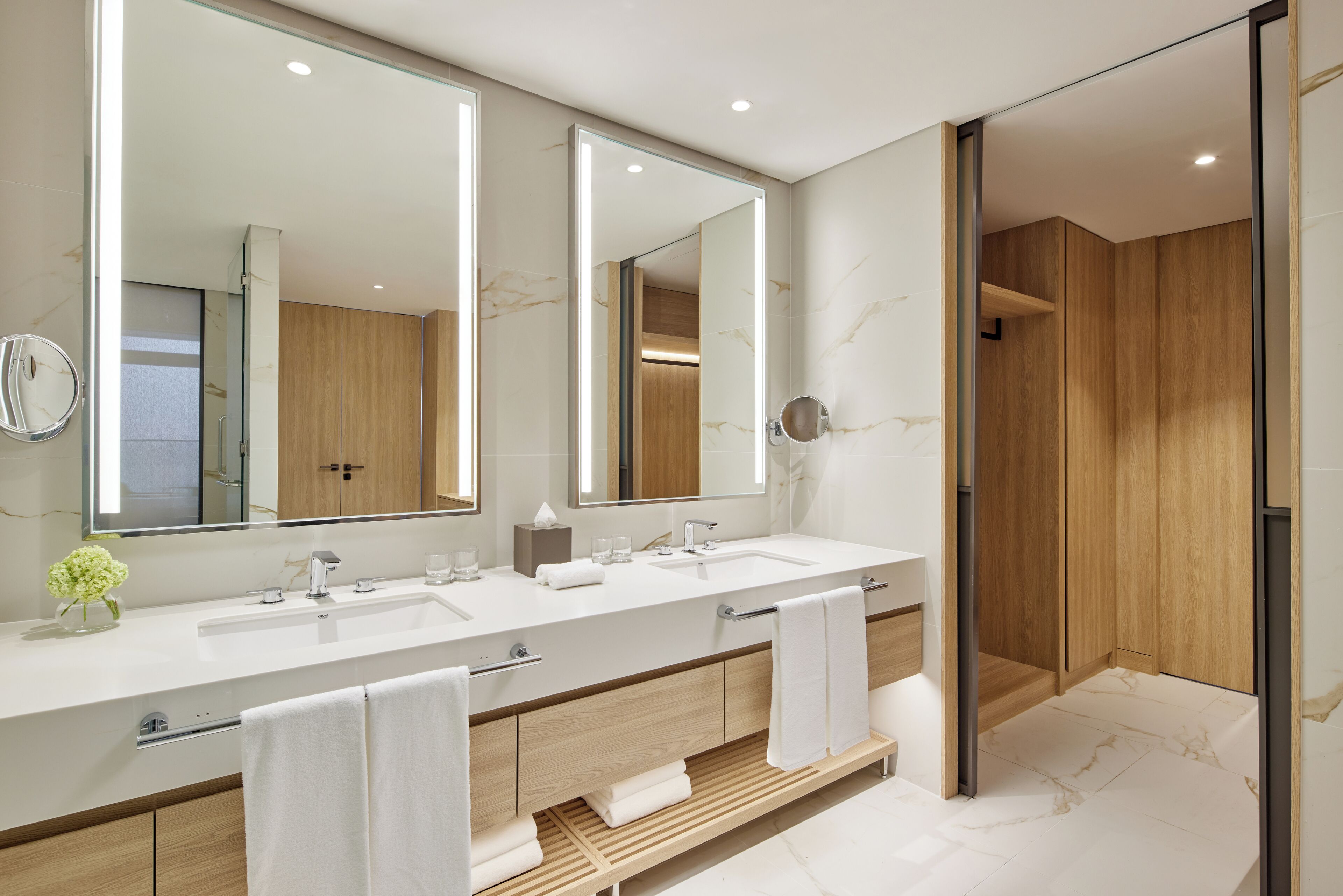 Un baño moderno con dos lavamanos, un espejo grande y muebles de madera.