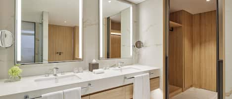 A modern bathroom with two sinks, a large mirror, and wooden cabinetry.