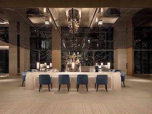 A modern bar area with a central counter, multiple seating options, and a chandelier. - Shillamonogram Gangneung Hotel (Gangneung)