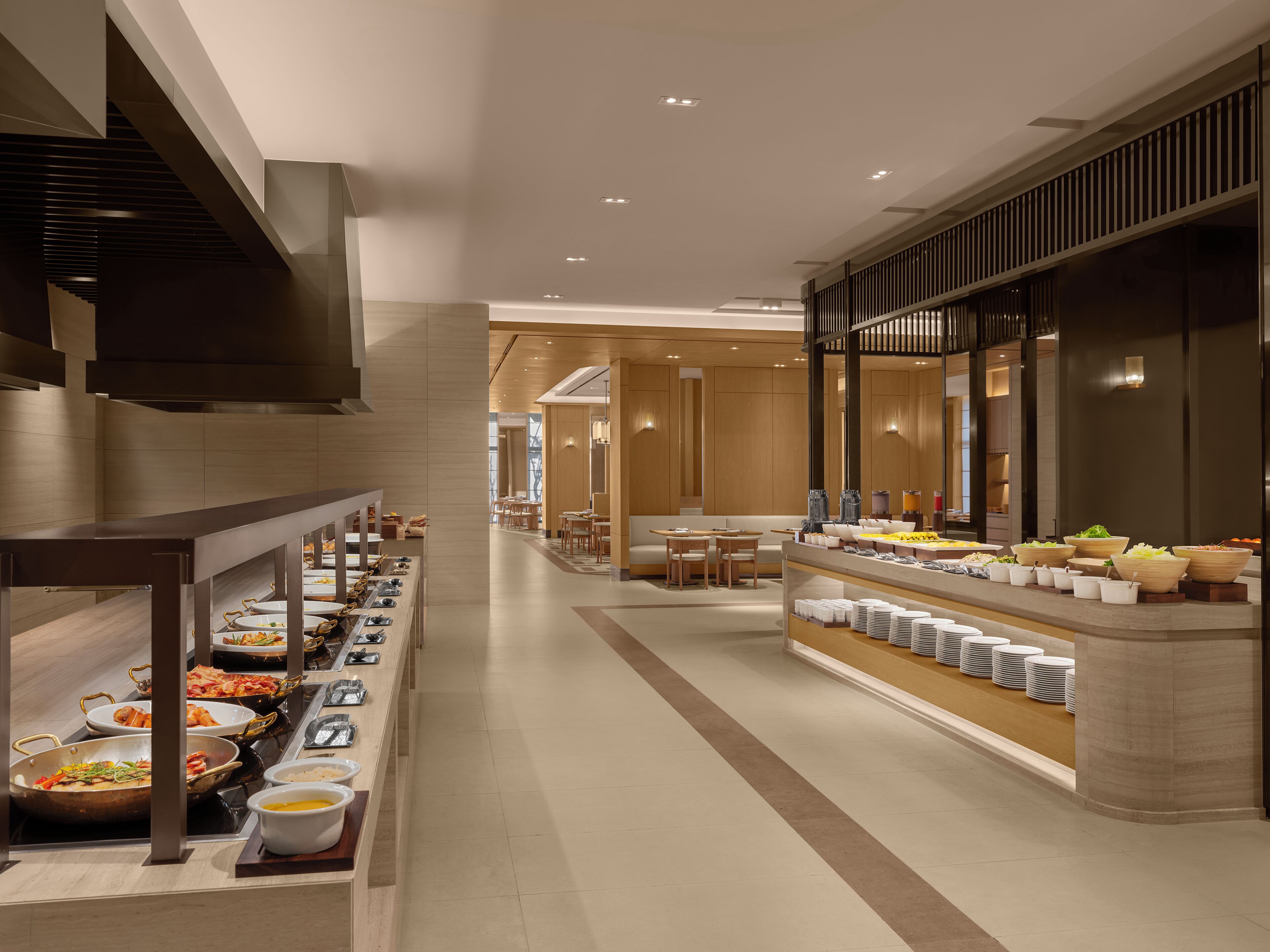 Un moderno vestíbulo de hotel con una zona de buffet que ofrece diferentes puestos de comida y arreglos de asientos.