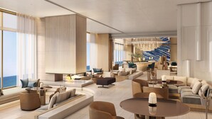 Eine großzügige, moderne Hotelhalle mit einer großartigen Sitzecke, einer Bar und Blick auf den Ozean.