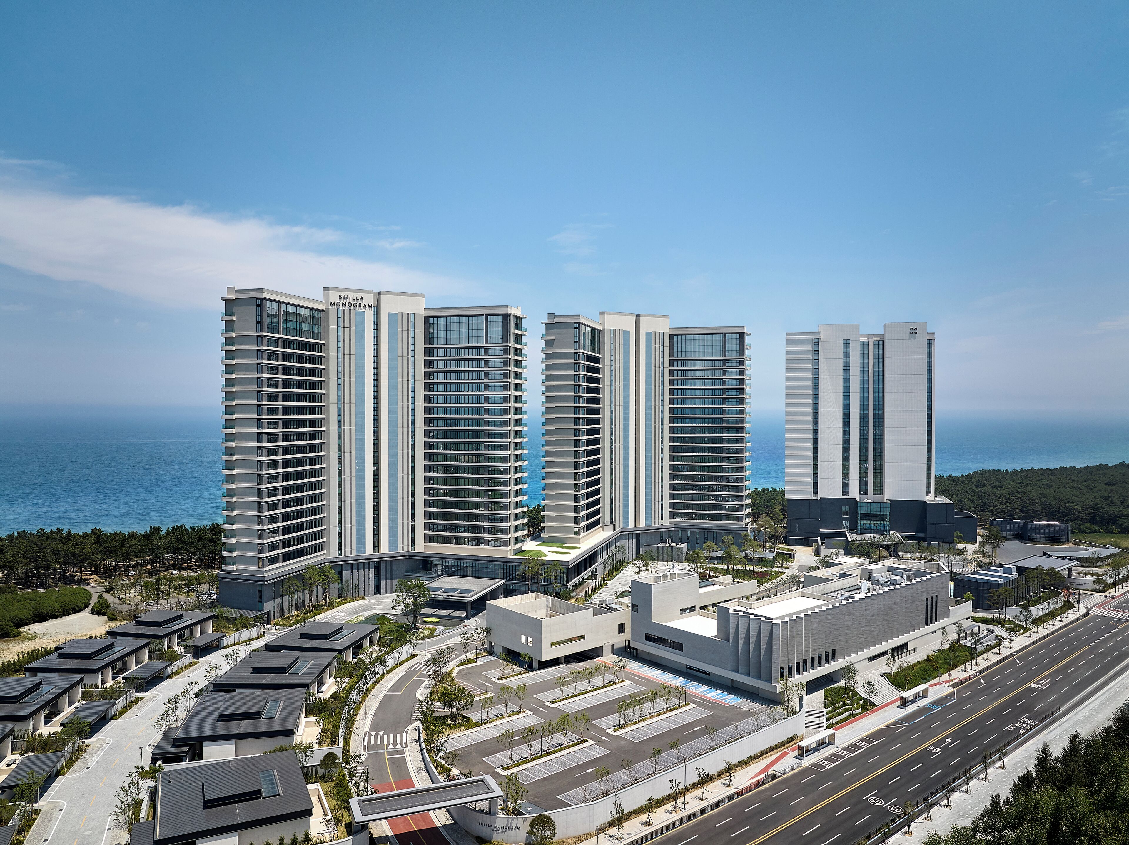 Un complexe immobilier moderne composé d’un ensemble de tours à étages multiples, d’un espace de stationnement et offrant une vue sur la mer.