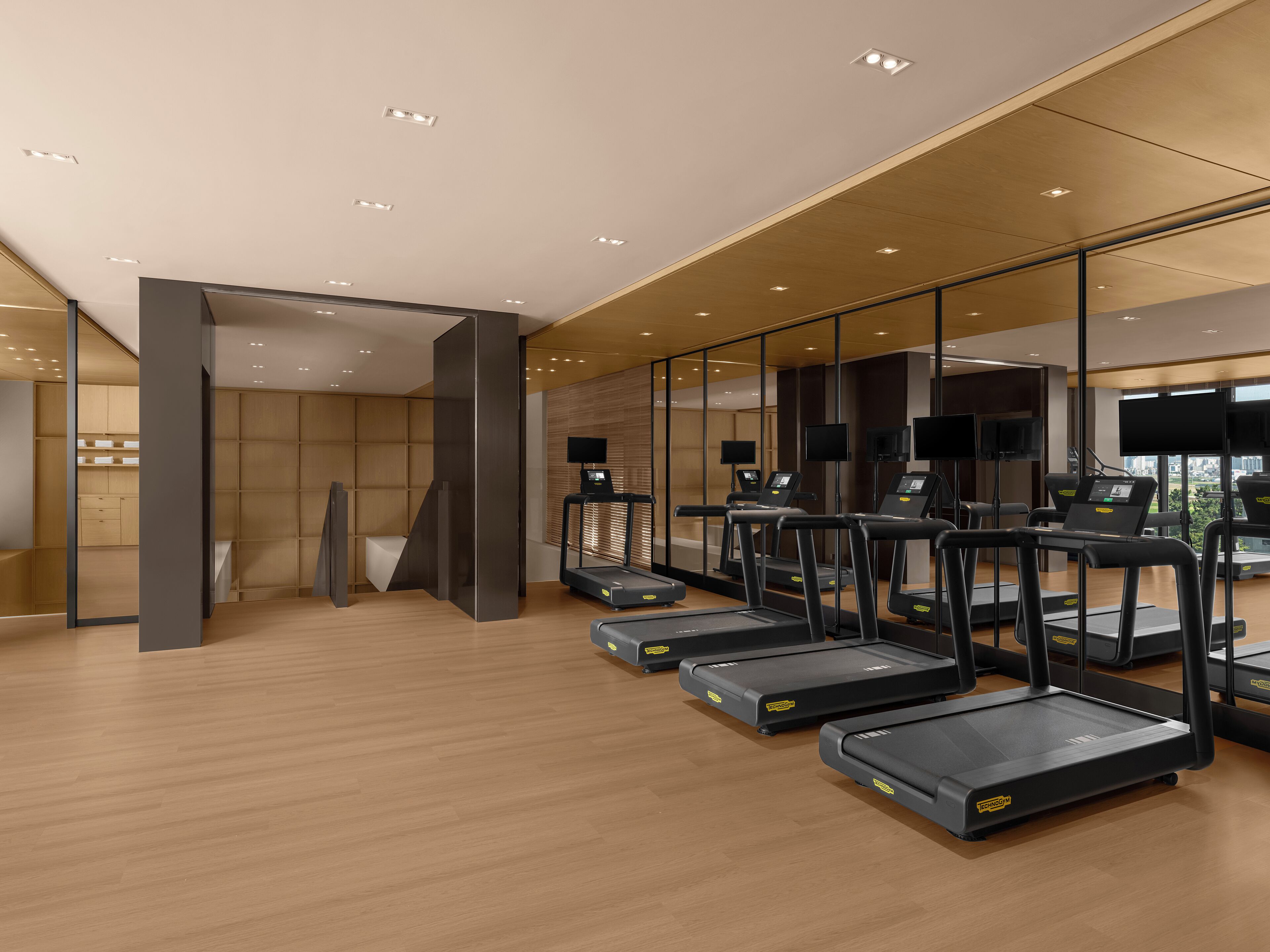 Un gimnasio moderno con cintas de correr, equipo de ejercicio y un amplio ventanal con vistas a la ciudad.