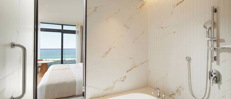 A modern bathroom with a large mirror, a bathtub, and a shower.