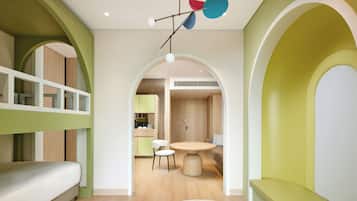 A modern interior with a bunk bed, a round dining table, and a kitchen in the background.