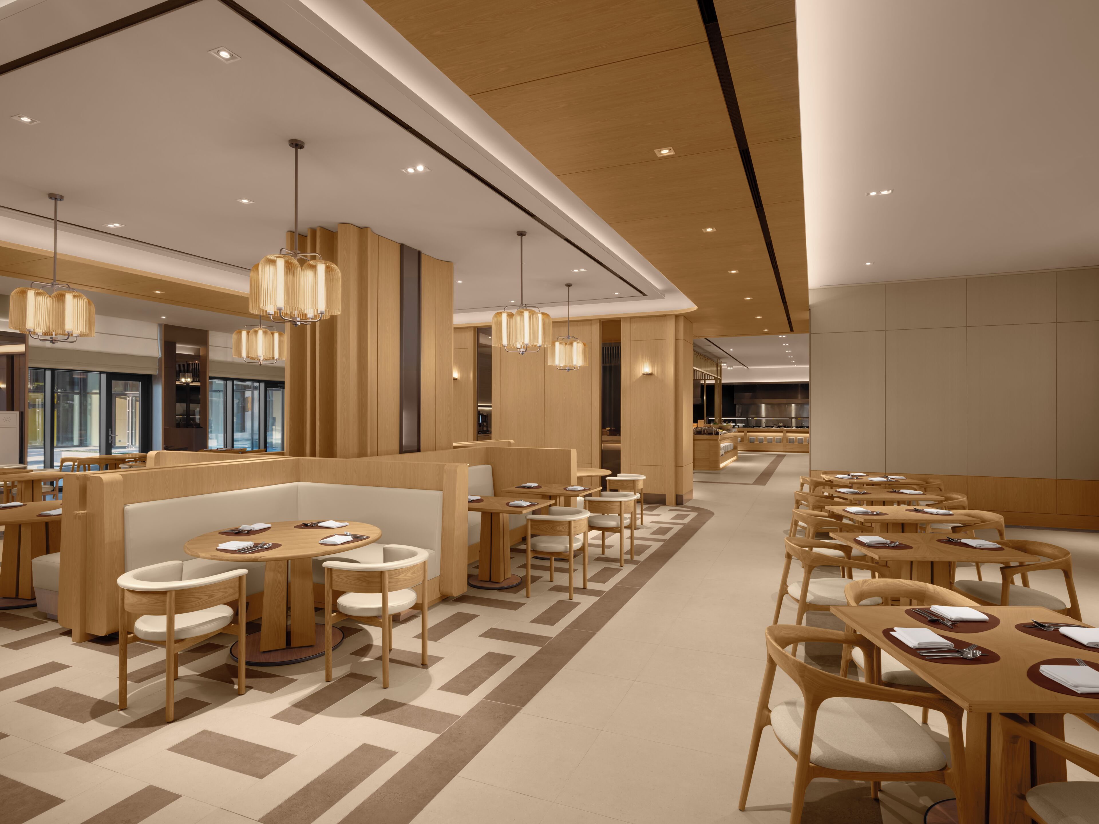 A modern restaurant with wooden furniture, pendant lighting, and a geometric floor pattern.