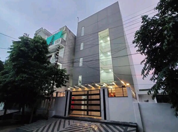 Un edificio moderno con un gran frente de vidrio, una entrada con portón y una escalera visible que lleva a la entrada.