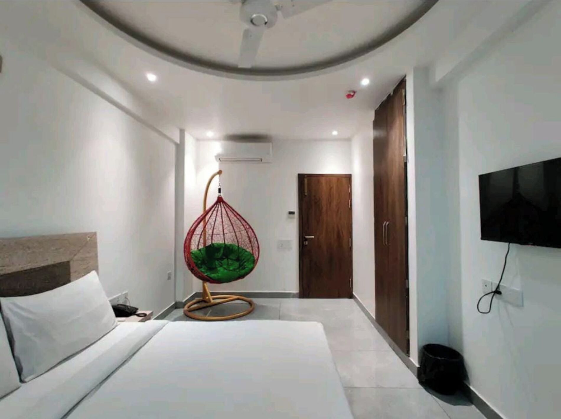 Una camera da letto moderna con una poltrona sospesa, un letto, una televisione e un armadio.