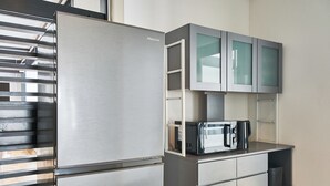 A compact kitchen with a stainless steel refrigerator, a microwave, and grey cabinets. - ASOBIBA Yoichi Onsenside (Yoichi)
