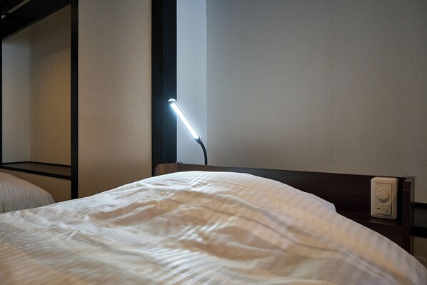 Una cama bien hecha con una colcha blanca y un cabecero con panel de control.