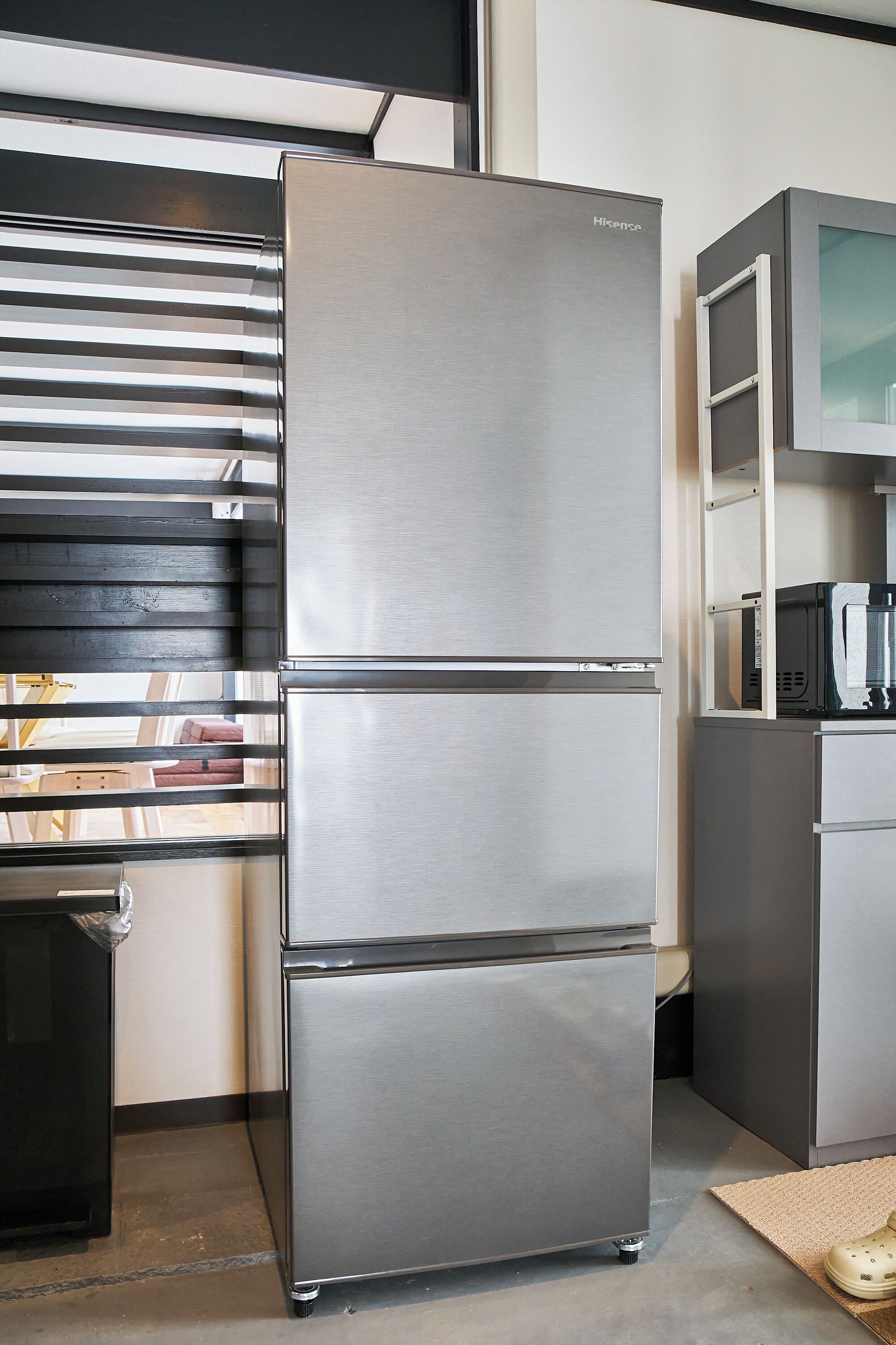 A stainless steel refrigerator with a Hisense logo, a microwave, and a small black appliance on top.