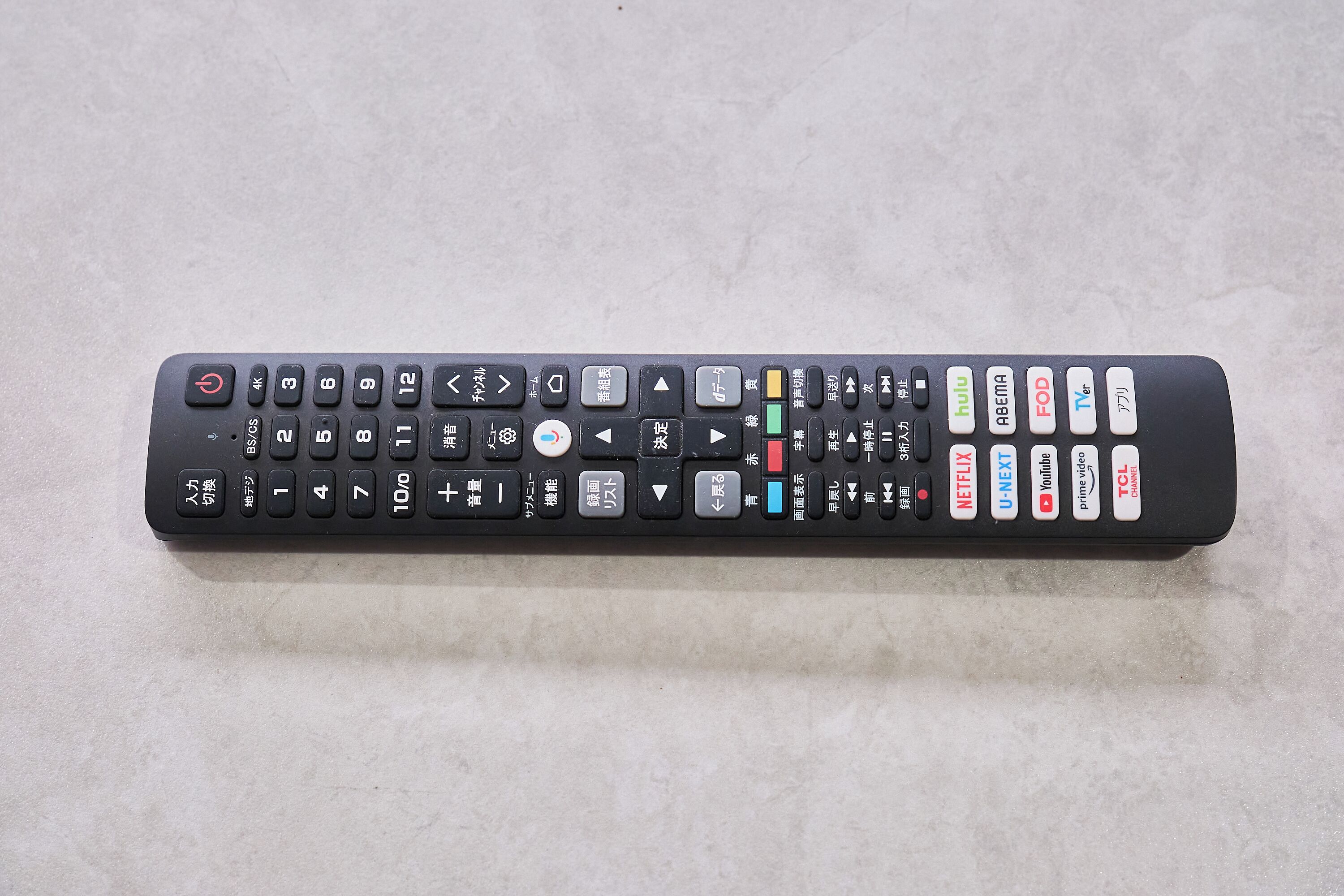 Een zwarte afstandsbediening met diverse knoppen, waaronder numerieke toetsen, richtingspijlen en functieknoppen voor diensten zoals Netflix, Hulu en YouTube.