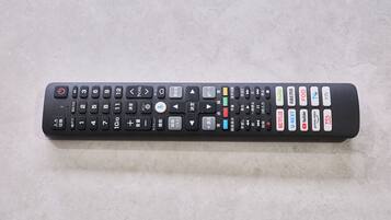 Een zwarte afstandsbediening met diverse knoppen, waaronder numerieke toetsen, richtingspijlen en functieknoppen voor diensten zoals Netflix, Hulu en YouTube.