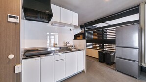 A modern kitchen with white cabinets, a stainless steel refrigerator, and a built-in oven. - ASOBIBA Yoichi Onsenside (Yoichi)