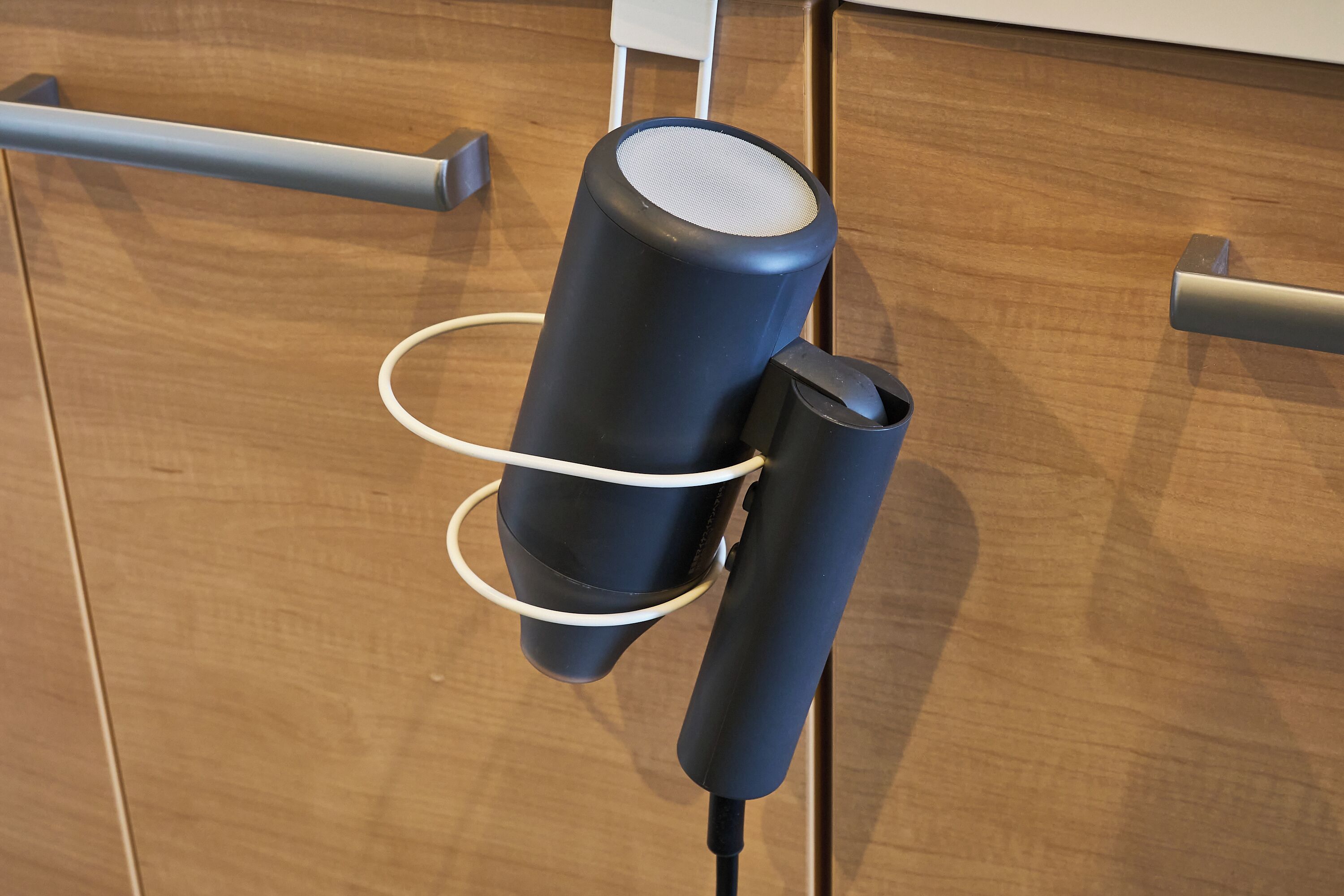 Een zwarte, draagbare speaker bevestigd aan een houten oppervlak met een witte kabel.