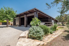 Ein modernes Gebäude mit überdachter Terrasse, gepflastertem Weg und verschiedenen Pflanzen.