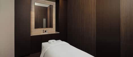 Un baño moderno con detalles en madera oscura, un espejo sobre un lavamanos y una toalla blanca sobre un banco.