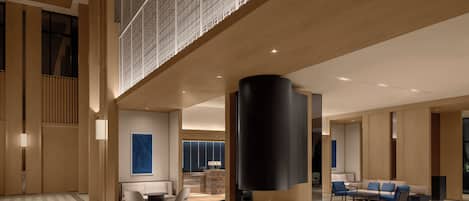 A spacious lobby with a central black cylindrical feature, seating areas, and a patterned floor.
