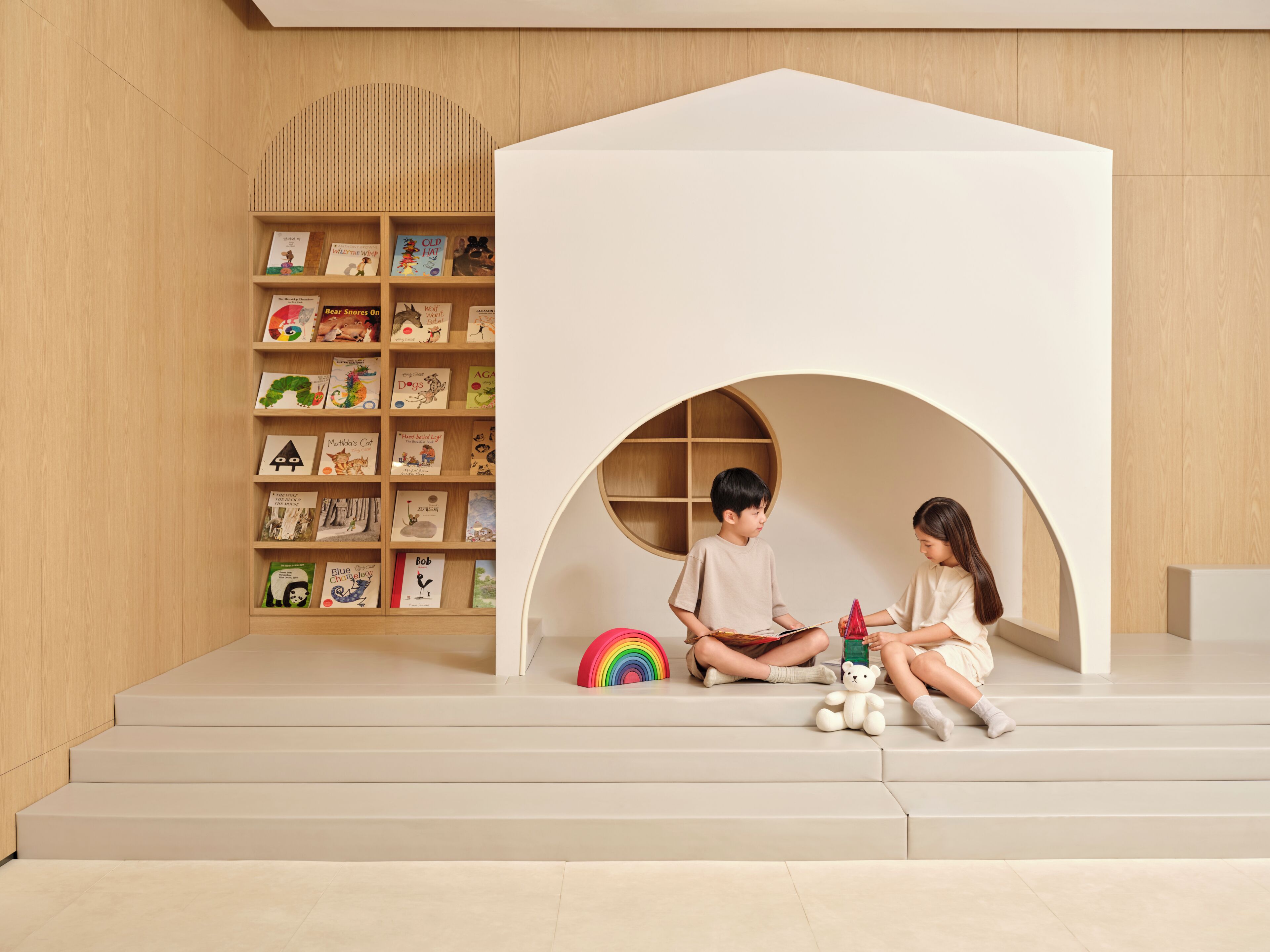 Een speelruimte voor kinderen, met een boekenkast en een witte speelhoes.