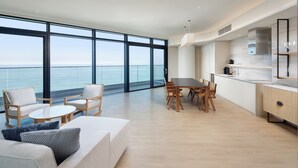 A modern living room with a large window, a dining area, and a kitchen with a view of the ocean. - Shillamonogram Gangneung Residence (Gangneung)
