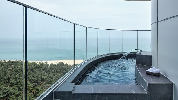 A modern infinity pool with a glass balustrade overlooking a beach and ocean. - Shillamonogram Gangneung Residence (Gangneung)