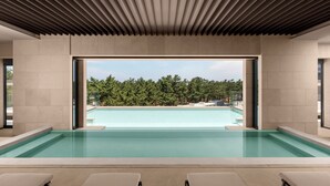 A modern indoor pool with clear blue water, surrounded by beige walls and a wooden ceiling. - Shillamonogram Gangneung Residence (Gangneung)