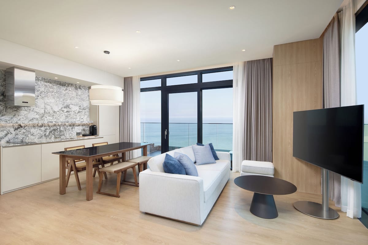 A modern living room with a sofa, dining table, and TV.