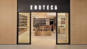 La entrada a una tienda de vinos con un diseño moderno, destacando un letrero llamativo y estantes repletos de botellas.