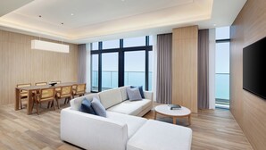 A modern living room with a sofa, dining table, and chairs, large windows with a view, and a flat-screen TV. - Shillamonogram Gangneung Residence (Gangneung)