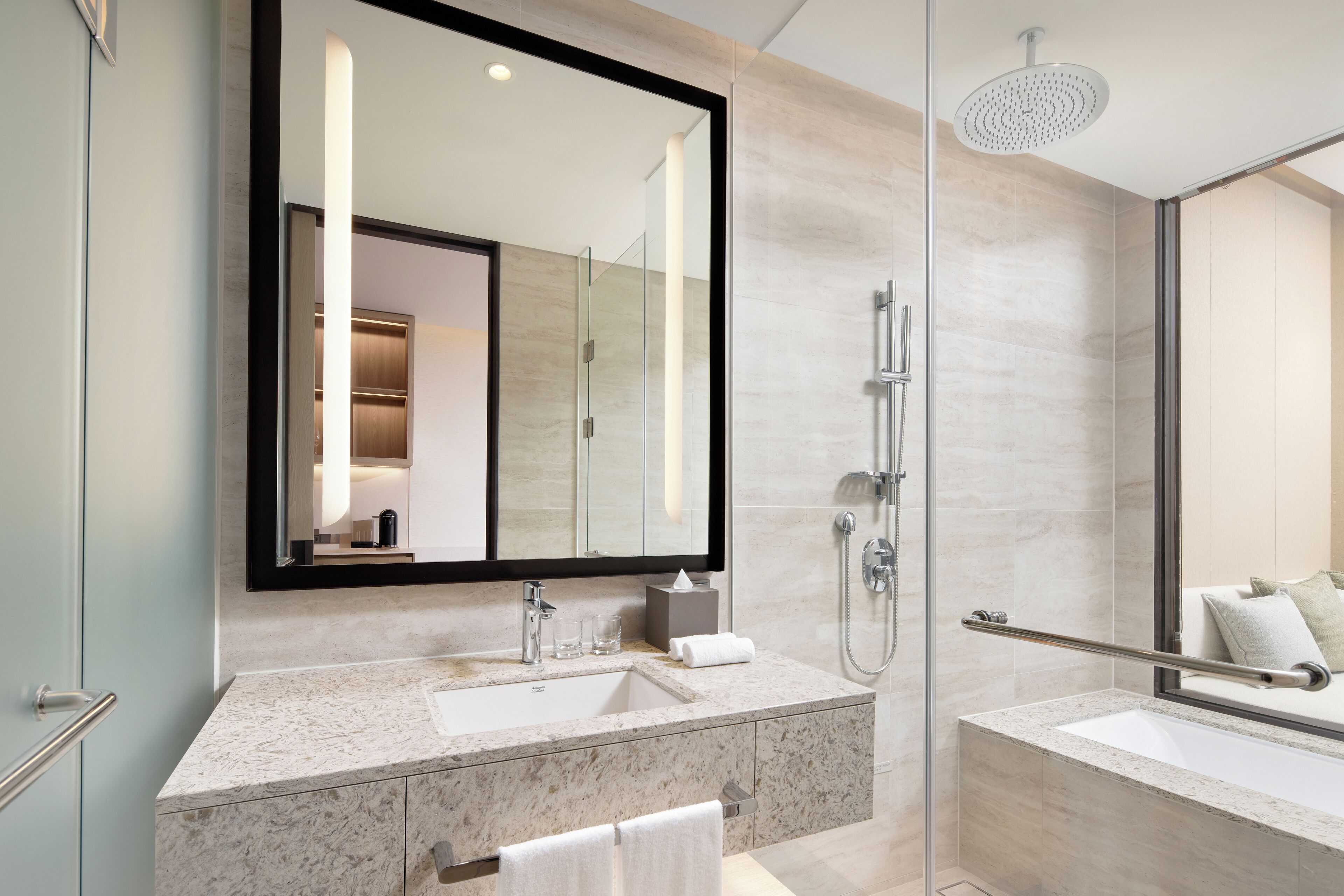 A modern bathroom with a large mirror, a sink, a shower area, and a bathtub.