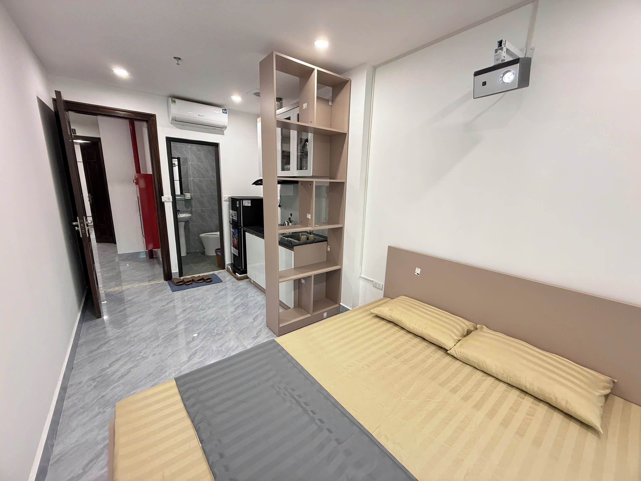 Un dormitorio moderno con cama, armario empotrado, baño y zona de cocina.