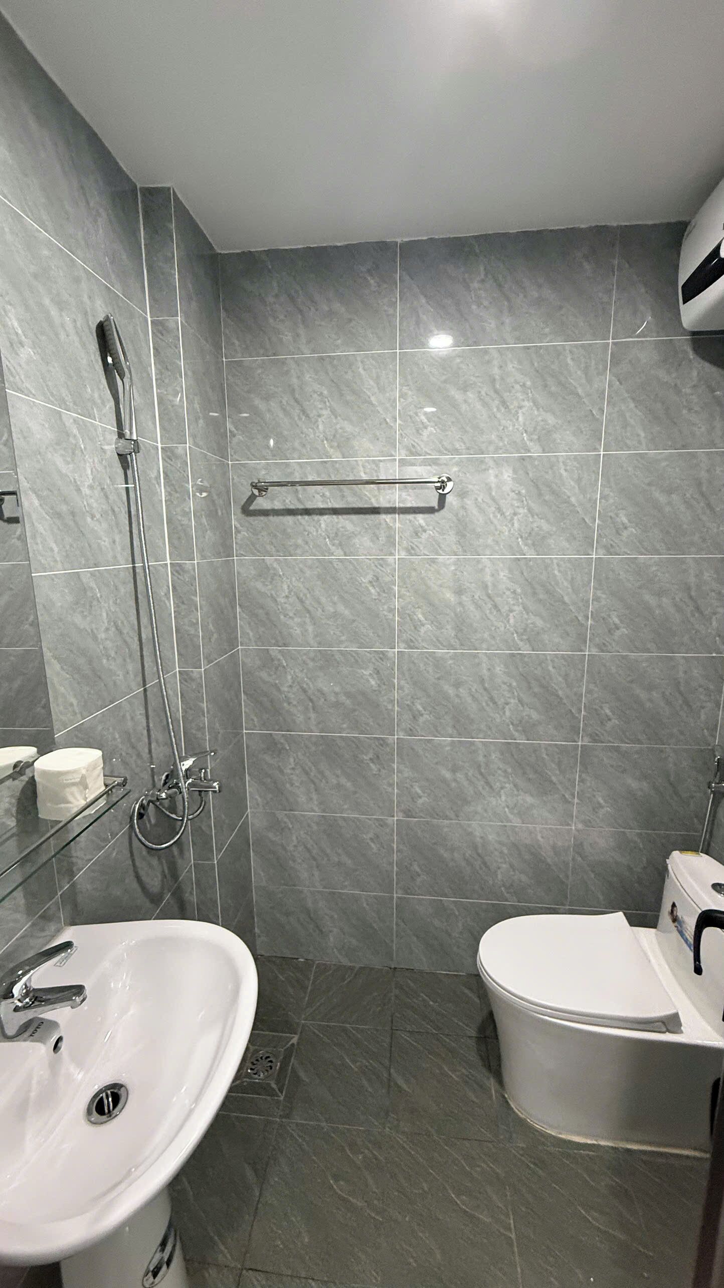 A modern bathroom with a shower, toilet, and sink.