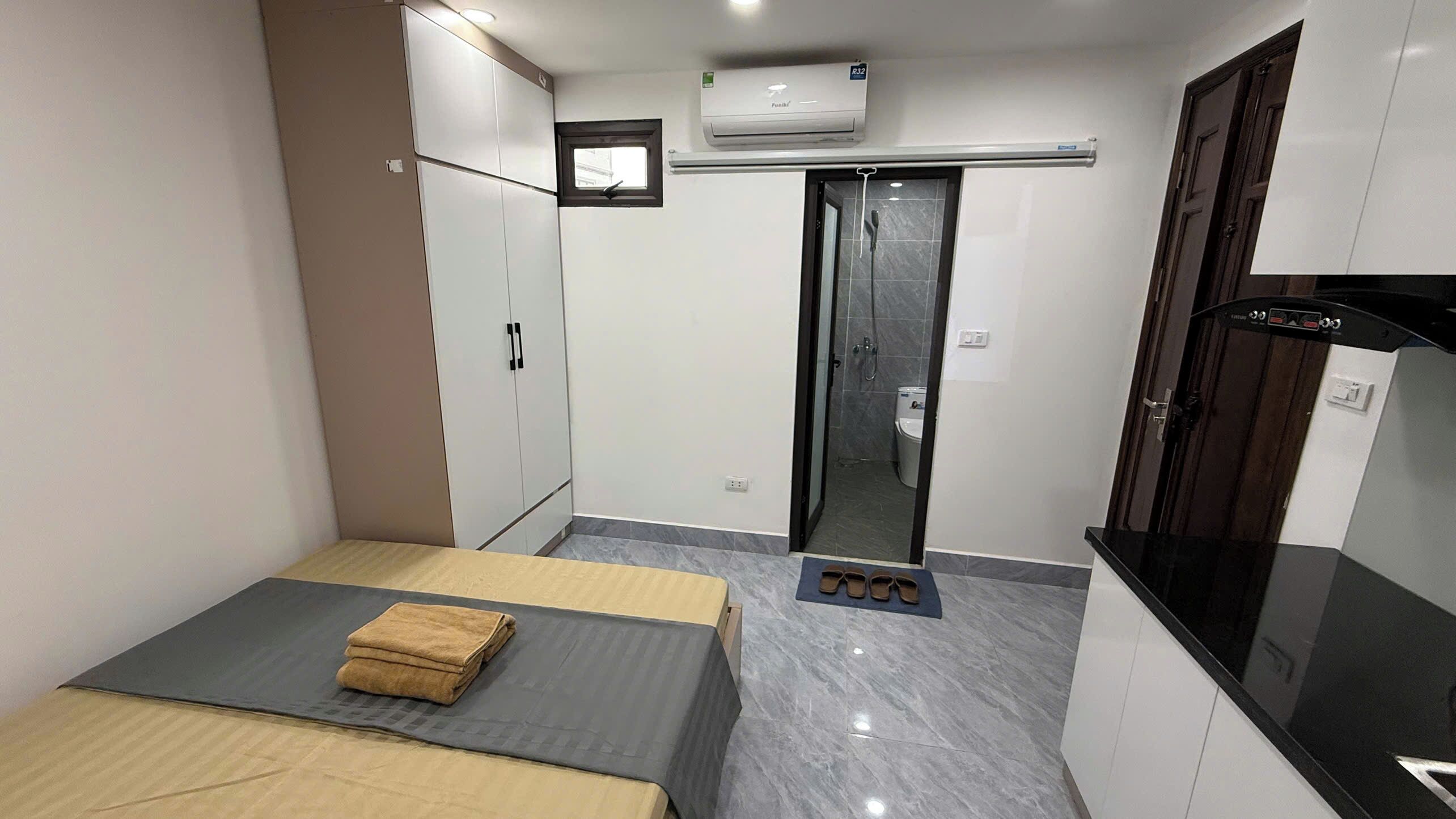 A compact bedroom with a bed, wardrobe, and a small kitchenette.